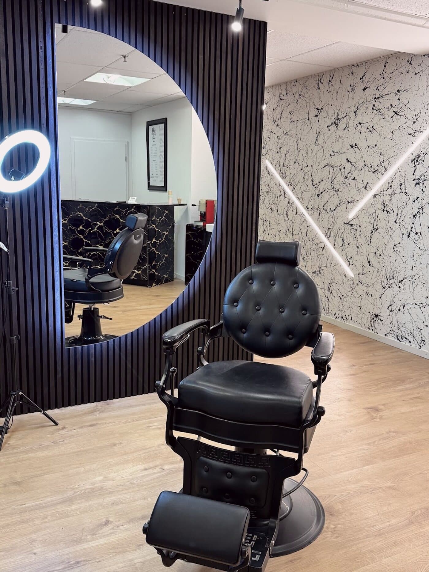 Der Barber-Stuhl bei The Gentleman Coiffeur — schwarzes Leder, Marmor und warmes Licht